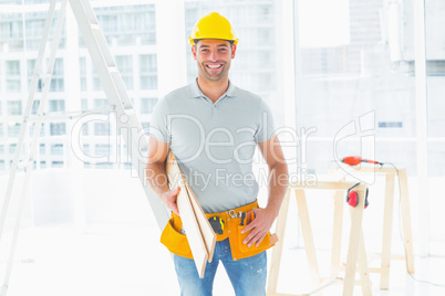 Male carpenter carrying planks in building