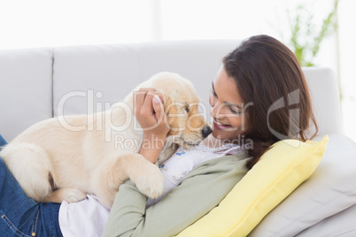 Woman playing with puppy while lying on sofa