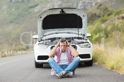 Stressed man sitting after a car breakdown