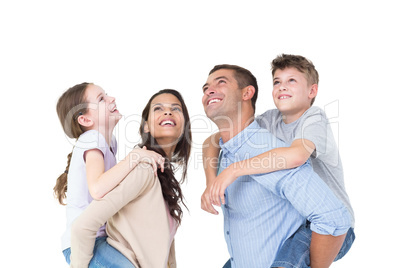Parents giving piggyback ride to children while looking up
