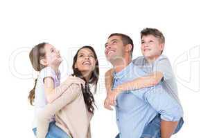 Parents giving piggyback ride to children while looking up