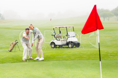 Golfing couple putting ball together