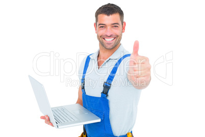 Portrait of handyman with laptop gesturing thumbs up