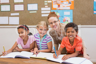 Teacher and pupils working at desk together