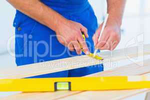 Carpenter marking on plank with tape measure