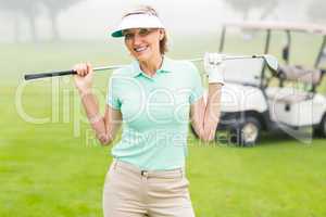 Happy golfer with golf buggy behind