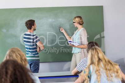 Student and teacher pointing at blackboard in class