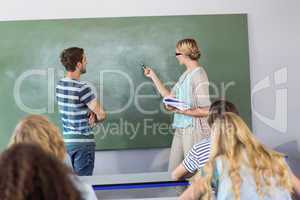 Student and teacher pointing at blackboard in class