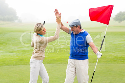 Golfing couple high fiving on the golf course