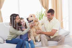 Family stroking dog while sitting on sofa