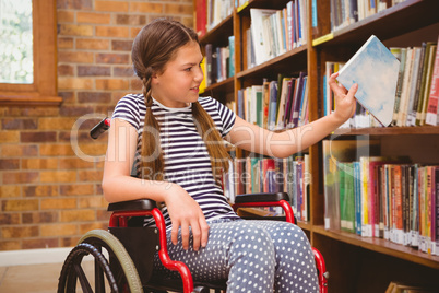 Girl in wheelchair selecting book in library