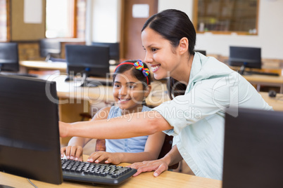 Cute pupil in computer class with teacher