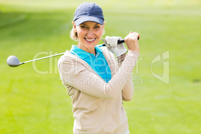 Female golfer taking a shot and smiling at camera