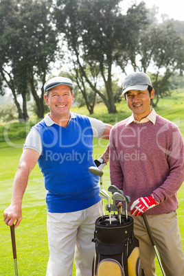 Golfing friends smiling at camera holding clubs