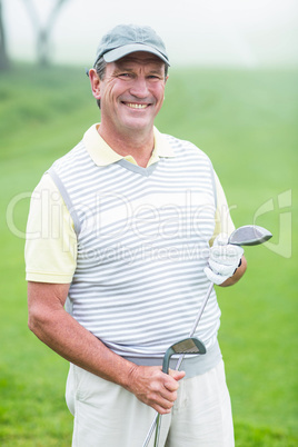 Cheerful golfer smiling at camera holding his club