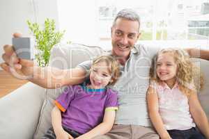 Father taking selfie with children on sofa