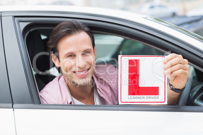 Learner driver smiling and holding l plate