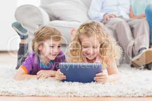 Brother and sister using digital tablet on rug