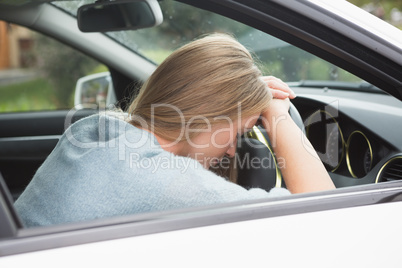 Tired woman asleep on steering wheel