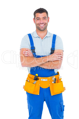 Repairman in overalls wearing tool belt standing arms crossed
