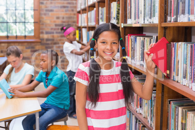 Cute pupil looking for books in library