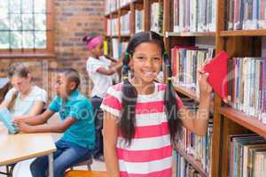 Cute pupil looking for books in library