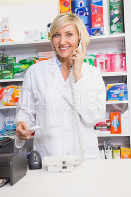 Smiling pharmacist on the phone reading prescription