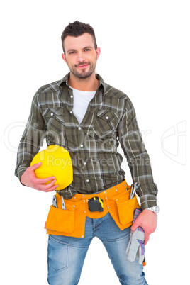 Handyman wearing tool belt while holding helmet and gloves