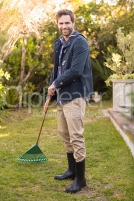 Handsome man raking in his garden