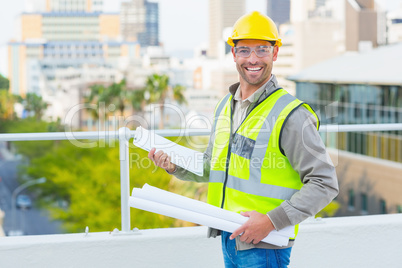 Smiling male architect with blueprints and clipboard