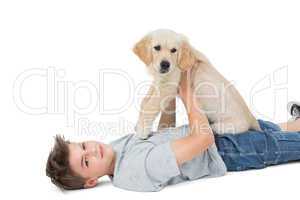 Boy holding puppy while lying over white background