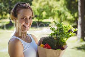Fit woman with paper bag of vegetables