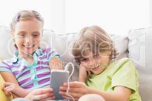 Siblings listening music through mobile phone at home