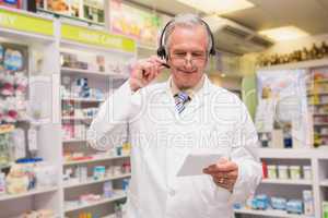Senior pharmacist with headphone reading prescription