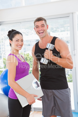 Smiling man lifting dumbbell with trainer