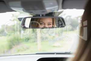 Young woman in the drivers seat looking in the mirror