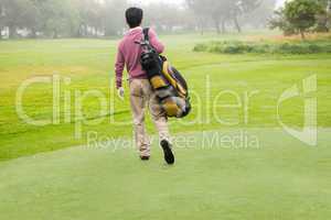Golfer walking away holding golf bag