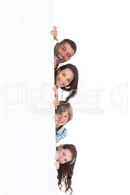 Happy family hiding behind billboard