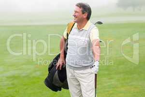 Handsome golfer standing with golf bag