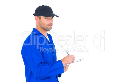 Mechanic in blue overalls writing on clipboard