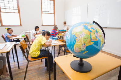 Cute pupils and teacher in classroom with globe