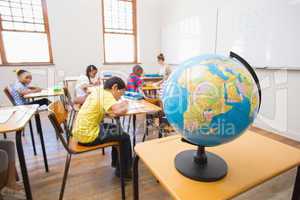 Cute pupils and teacher in classroom with globe