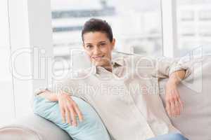 Happy woman sitting comfortably on sofa