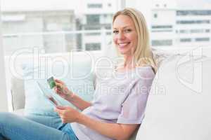 Happy woman with digital tablet and credit card on sofa