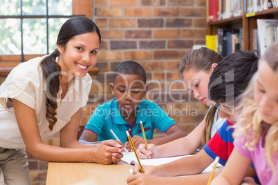 Pretty teacher helping pupils in library Pretty teacher helping pupils in library