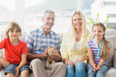 Portrait of happy family sitting with cat on sofa