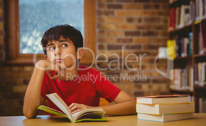 Thoughtful boy reading book in library