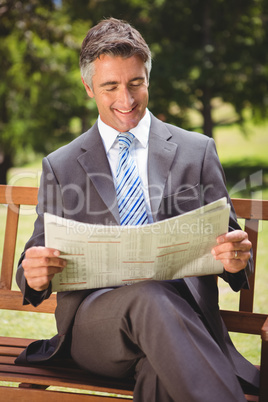 Businessman reading newspaper in the park