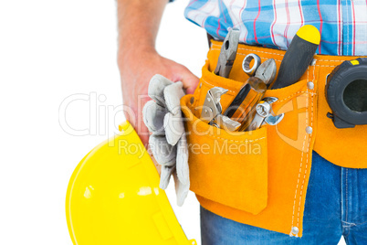 Manual worker wearing tool belt while holding gloves and helmet