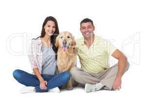 Happy couple with dog sitting over white background